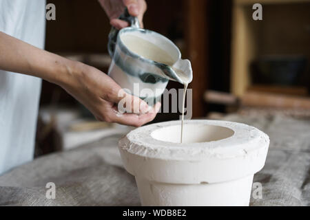 Mani femminili in ceramica versare la miscela in uno stampo. Foto Stock