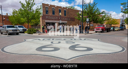 Winslow Arizona, Stati Uniti. Il 23 maggio 2019. La storica Route 66 segno sulla strada, turisti guardando la Standin all'angolo statua, Foto Stock