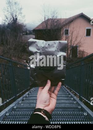 Scatto verticale di una persona che tiene un sacchetto d'argento con una scala in metallo sullo sfondo Foto Stock