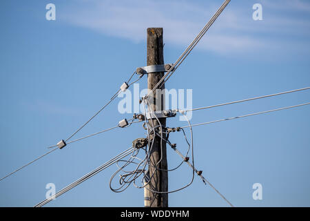 Massa del telefono disordinata di fili o cavi collegati a un legno palo del telegrafo in campagna in Italia Foto Stock