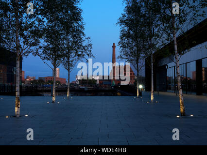 Guardando attraverso un gap in isola di Mann edifici verso il Royal Albert Dock complessa al crepuscolo. Foto Stock