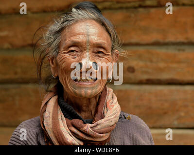 Vecchio Apatani indiano donna tribale con legno nero tappi naso (yawping hullo) e distintivo faccia tribale tatuaggio pone per la fotocamera. Foto Stock