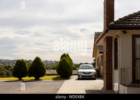 Casa & car arroccato sulla cima di una collina con vista suburbana. Foto Stock