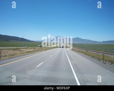 Southbound Interstate 15 nello Utah, Stati Uniti d'America. Montagne distanti nel punto di fuga. Quasi vuoto US Highway. Interstate Highway in Stati Uniti occidentali. Foto Stock
