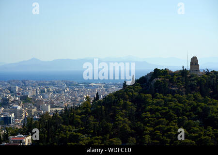 Vista dall'Acropoli, con il monumento di Filopappos Filopappos sulla collina che si affaccia verso il golfo Saronico Foto Stock