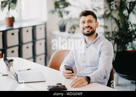 Ritratto di imprenditore parlando al telefono cellulare in ufficio Foto Stock