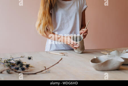 Irriconoscibile la donna lavora con argilla mug in piedi in una tabella in studio Foto Stock