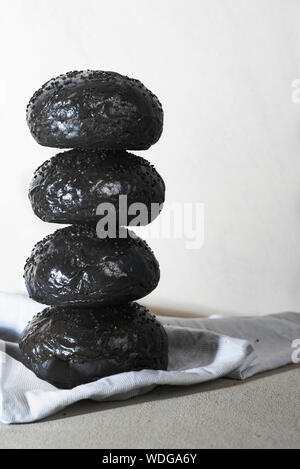 Pane nero realizzata con inchiostro di calamari, strano cibo. Hamburger fatti in casa pane. Pila di pane nero panini Foto Stock