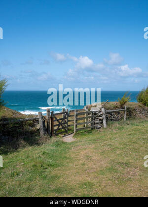Un di legno kissing gate sulla costa sud-ovest vicino percorso Porthcothan Cornwall Regno Unito con una vista del mare Foto Stock