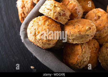 Concetto di alimenti freschi di forno in casa burrosa, salato prosciutto e formaggio scones su sfondo nero Foto Stock