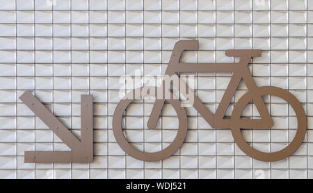 Amsterdam, Paesi Bassi - 30 Giugno 2019: Closeup gigante di parcheggio bici segno con indicatore di direzione giù sul muro bianco a IJdok. Foto Stock