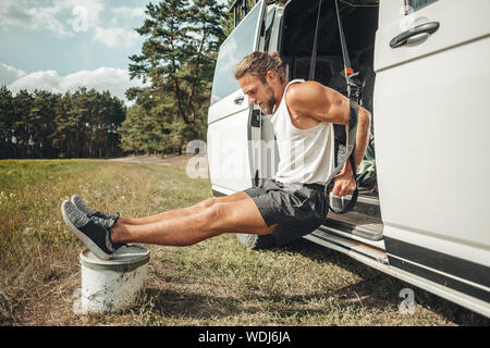 Uomo che fa un allenamento accanto al suo camper-van Foto Stock