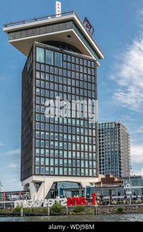 Amsterdam, Paesi Bassi - 30 Giugno 2019: un'dam lookout tower sotto il cielo blu con alcune nuvole bianche. IJ acqua nella parte anteriore. Iconico segno di Amsterdam. Ha osato Foto Stock