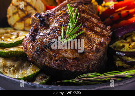 Succosa bistecca e verdure grigliate in una padella. Close-up Foto Stock