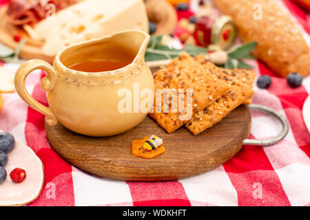 Elegante pic nic sul prato verde. Cornetti freschi e una teiera con il tè su un copriletto vicino a una femmina di vimini hat. Instagram contenuto. Foto Stock