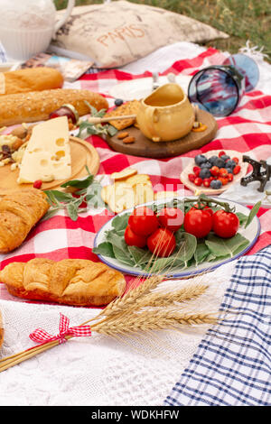 Elegante pic nic sul prato verde. Cornetti freschi e una teiera con il tè su un copriletto vicino a una femmina di vimini hat. Instagram contenuto. Foto Stock