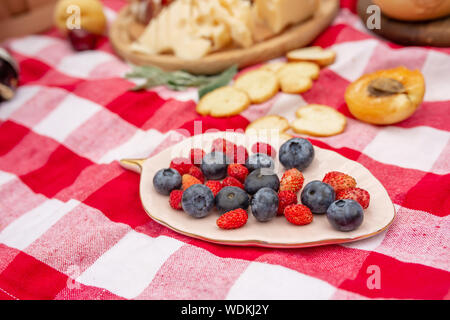 Elegante pic nic sul prato verde. Cornetti freschi e una teiera con il tè su un copriletto vicino a una femmina di vimini hat. Instagram contenuto. Foto Stock