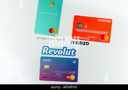 Starling, Monzo, Revolut carte bancarie poste una accanto all'altra. Concetto di concorrenza. Le informazioni sensibili è coperto con gli adesivi con cifre fittizia. Foto Stock