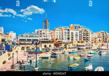 Lungomare di Spinola bay con colorate barche da pesca a giornata di sole. St Julians, Malta Foto Stock