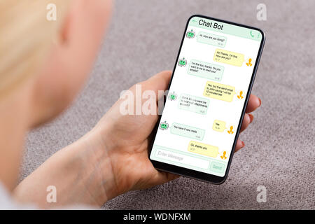 Close-up di donna utilizzando Chat Bot applicazione per chat sullo smartphone Foto Stock