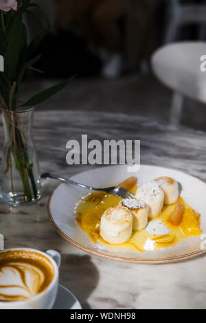 Cottage cheese pancakes con marmellata di arancione sulla piastra bianca, tavola di marmo, al ristorante. Luce naturale e shadow alimentare il concetto di fotografia Foto Stock