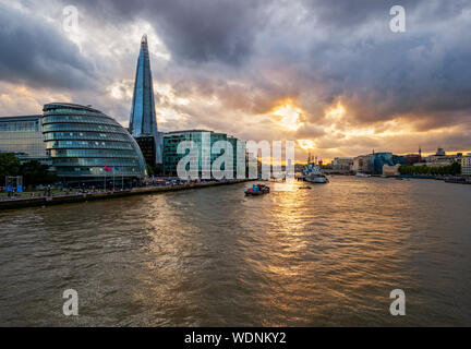 Il fiume Tamigi illuminato dal tramonto con i famosi punti di riferimento lungo la riva del fiume a Londra in Inghilterra Foto Stock