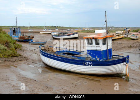 Piccole barche da pesca sul fango con la bassa marea, Brancaster Staithe, Norfolk, Inghilterra Foto Stock