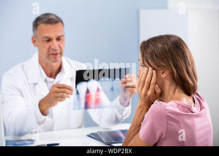 Donna con Dente dolore seduto di fronte medico controllo apparecchiature odontoiatriche a raggi X Foto Stock