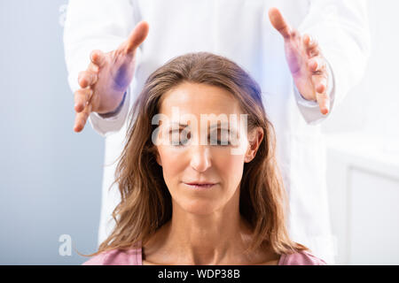 Close-up di un terapeuta mano dando reiki guarigione trattamento per donna In Spa Foto Stock