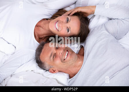 Angolo di Alta Vista di Felice Coppia Matura giacente sul letto Foto Stock