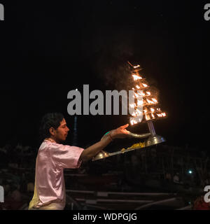 Indian sacerdote Indù portando candele accese durante la ganga Aati rituale al Dashashwamedh Ghat di Varanasi, Uttar Pradesh, India, Asia Foto Stock