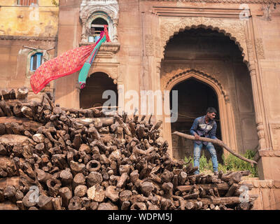 Uomo indiano impilatura legno per roghi a Manikarnika (Combustione) Ghat di Varanasi, Uttar Pradesh, India, Asia Foto Stock