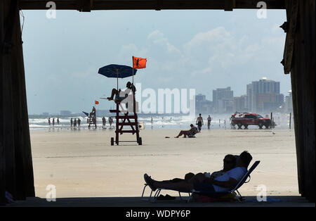 Titusville, FL, Stati Uniti d'America. Il 29 agosto, 2019. Le persone a rilassarsi all'ombra sotto il Daytona Beach pier diversi giorni prima dell'Uragano Dorian che dovrebbe diventare un uragano di categoria 4 prima di fare approdo in Florida il giorno della festa del lavoro. Credito: Paul Hennessy SOPA/images/ZUMA filo/Alamy Live News Foto Stock