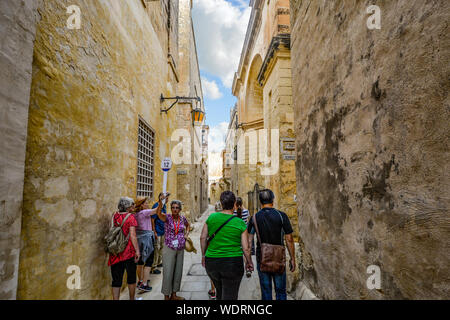 Una guida turistica attende per il suo gruppo di tour per recuperare il ritardo accumulato nel corso di un tour a piedi della medioevale città fortificata di Mdina, Malta Foto Stock