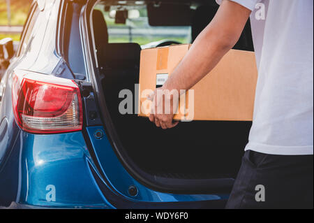 Uomo di erogazione è in grado di fornire una scatola di cartone per i clienti tramite auto privata porta trunk. La gente di stili di vita e di occupazione di business concetto. Giovane maschio courie Foto Stock