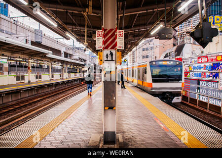 Dic 5, 2018 Tokyo, Giappone - JR Chuo Line approching treno stazione di Kanda piattaforma con pochi passeggeri in attesa dietro la linea gialla. Foto Stock