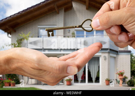 Agente immobiliare mano dare le chiavi di casa a un client nella parte anteriore della casa Foto Stock