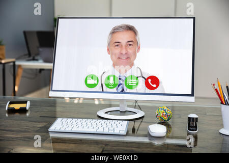 Medico sorridere mentre le videoconferenze su Computer in ospedale Foto Stock