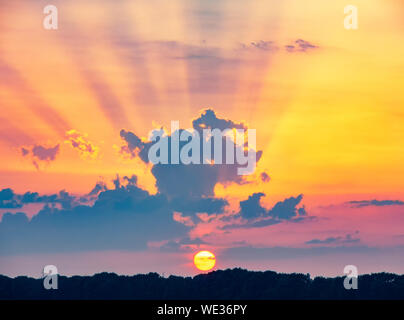 Regolazione del sole e dei raggi solari sulla colorata orange sky. Vivid paesaggio di campagna Foto Stock