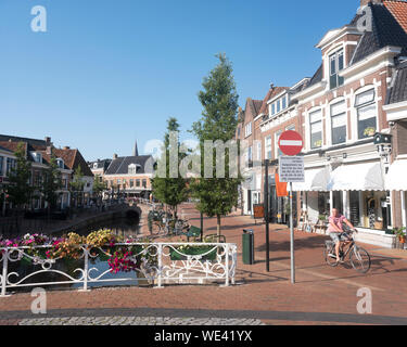 Uomo in bicicletta vicino al vecchio canale nel centro di dokkum nella provincia olandese della Frisia Foto Stock