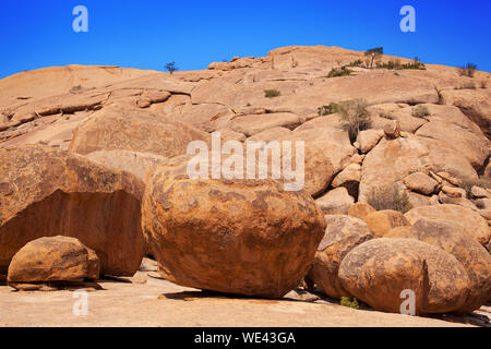 Red calvo picco di granito, cielo blu, sfondo round antiche pietre arancioni tori partito, Erongo mountains, Naukluft national park, Namib Desert, Namibia Foto Stock