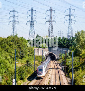 Un double-decker TGV Duplex con il treno ad alta velocità in livrea Carmillon sta entrando in un tunnel sotto una fila di torri di trasmissione sulla LGV Atlantique Stazione. Foto Stock