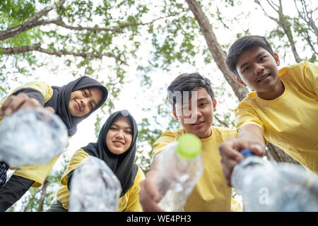 Gruppo di adolescenti asiatici volontari di prelevamento nel cestino della bottiglia al parco Foto Stock