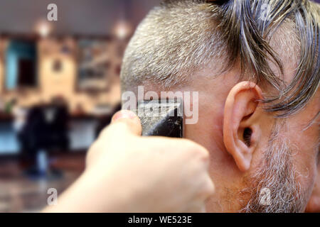 Barbiere facendo un taglio di capelli utilizzando trimmer macchina di taglio Foto Stock