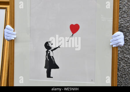 Londra, Regno Unito. Il 30 agosto, 2019. Anonimo artista di strada Banksy iconici lavoro Ragazza con palloncino passa sul display vicino a una delle posizioni originali artwork apparso a, Teatro Nazionale, South Bank di Londra, precedendo di un 'Banksy: non riesco a credere voi idioti effettivamente acquistare questo sh*t' solo online auction del lavoro dell'artista, in corrispondenza Christies.com. Banksy, ragazza con palloncino, 2004, preventivo: £50,000-70,000 London, Regno Unito - 30 August 2019 Credit: Nils Jorgensen/Alamy Live News Foto Stock