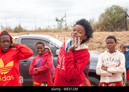 Mbabane, Swaziland - Agosto 31, 2017: gruppo di sorridenti africana di belle ragazze in rosso brillante vestiti all'aperto vicino fino Foto Stock