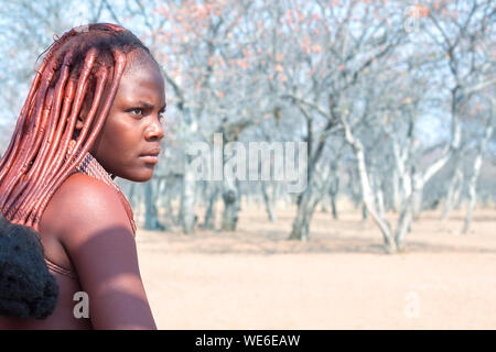 Otjikandero Villaggio Himba, Namibia - 8 Settembre 2017: Bella himba ragazza giovane con la nazionale di acconciatura tradizionali, anelli, collane e bracciali Foto Stock