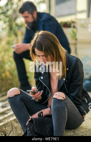 Donna e uomo di sedersi con il telefono cellulare e il giovane in amore, la comunicazione e la nuova tecnologia, blogging e sms Foto Stock