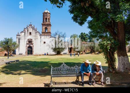 Messico, Michoacan stato, Tzintzuntzan, messicano due su di un banco prima della chiesa Foto Stock