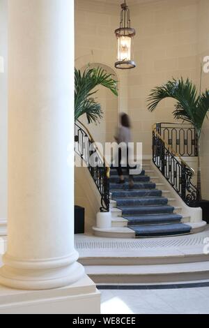 Francia, Parigi, Hotel du Louvre, donna salire le scale sotto il porticato della lobby dell'Hotel du Louvre appartenenti al gruppo hyatt Foto Stock
